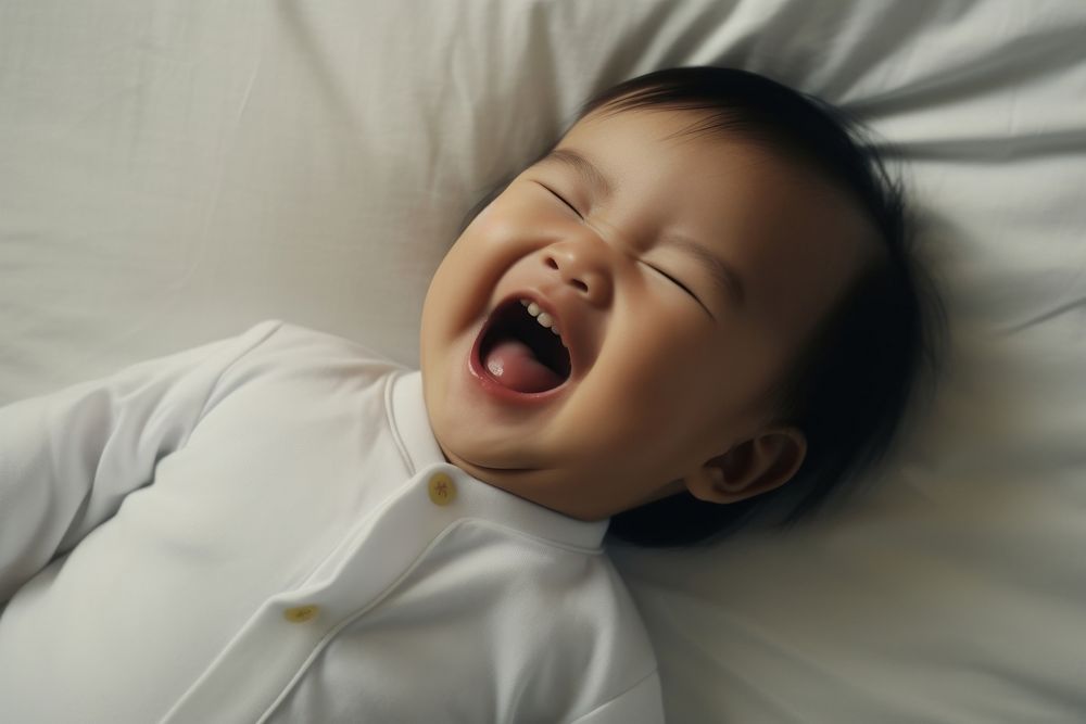 East Asian baby laughing yawning bed.
