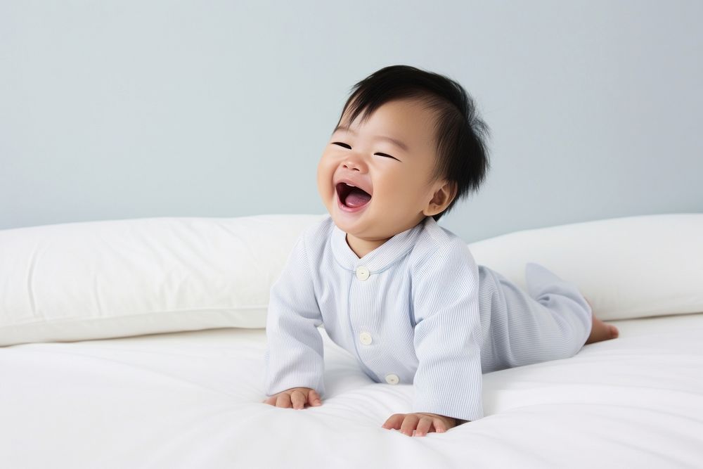 East Asian baby laughing bed comfortable.