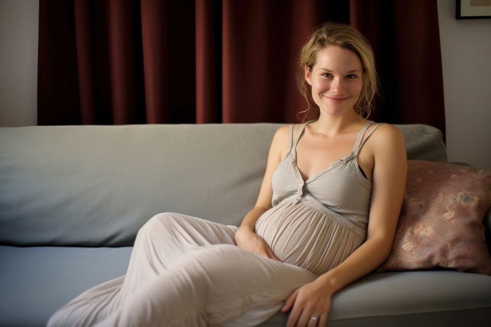 Pregnant british woman sitting furniture smiling.