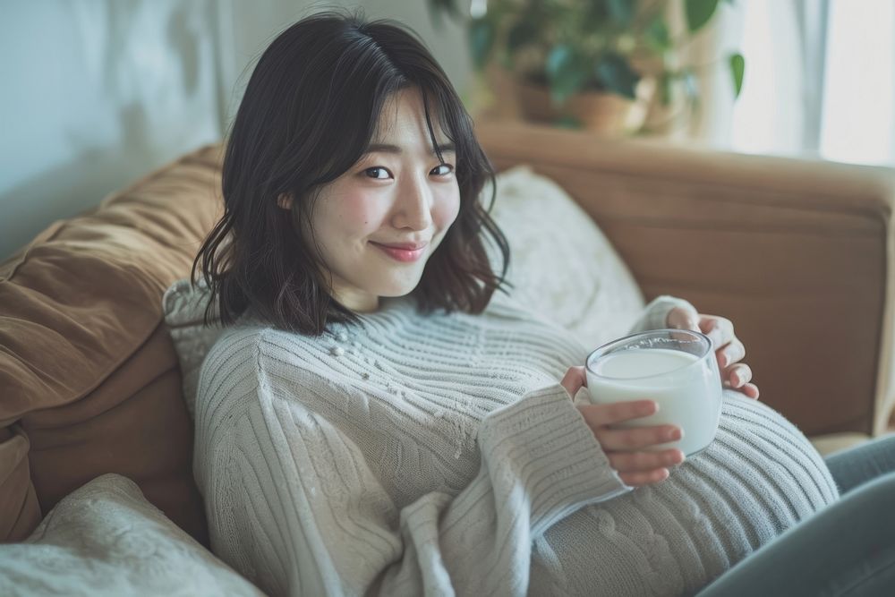 Pregnant korean woman drinking sitting smiling.