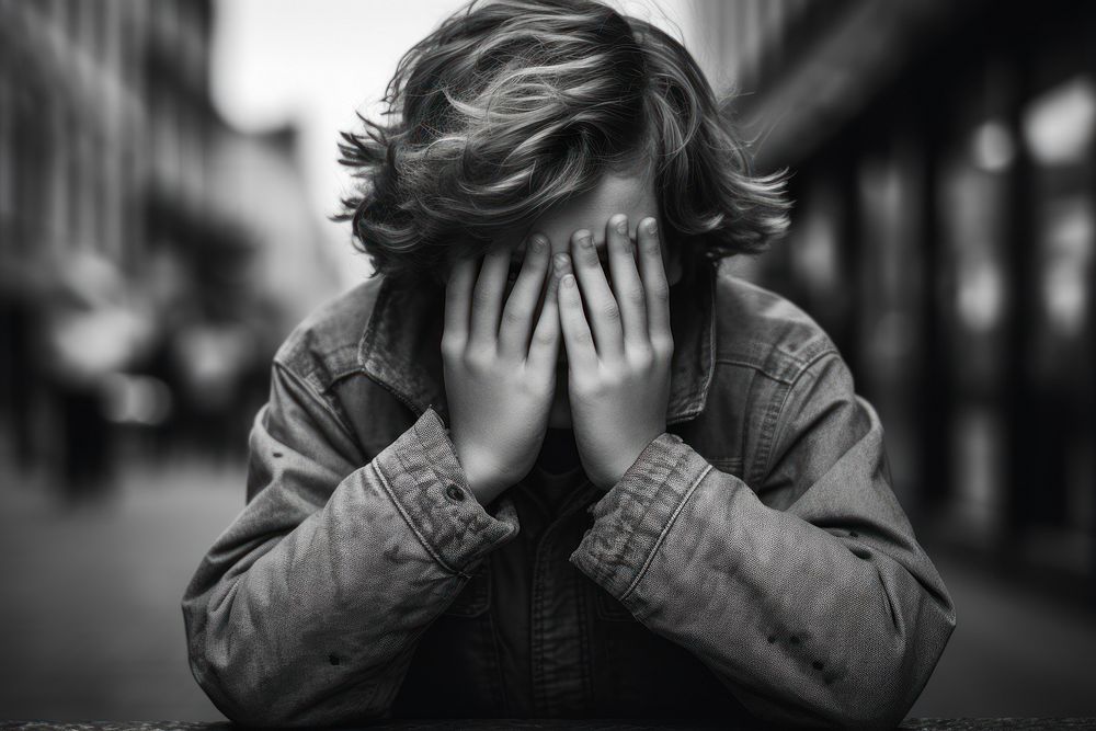 A boy covering his face photography portrait worried.