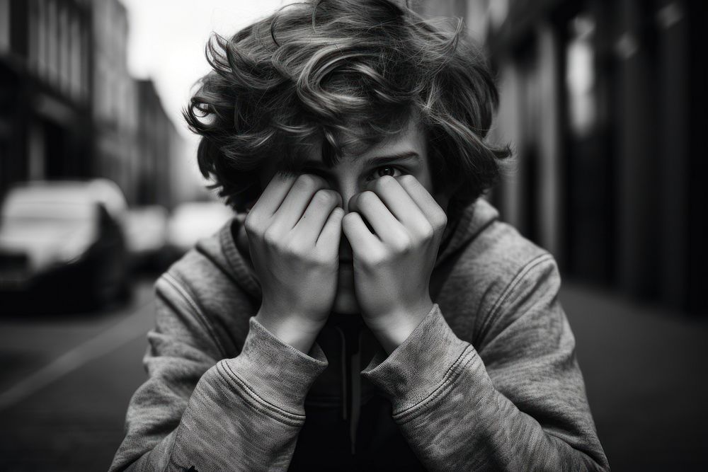 A boy covering his face photography portrait worried.