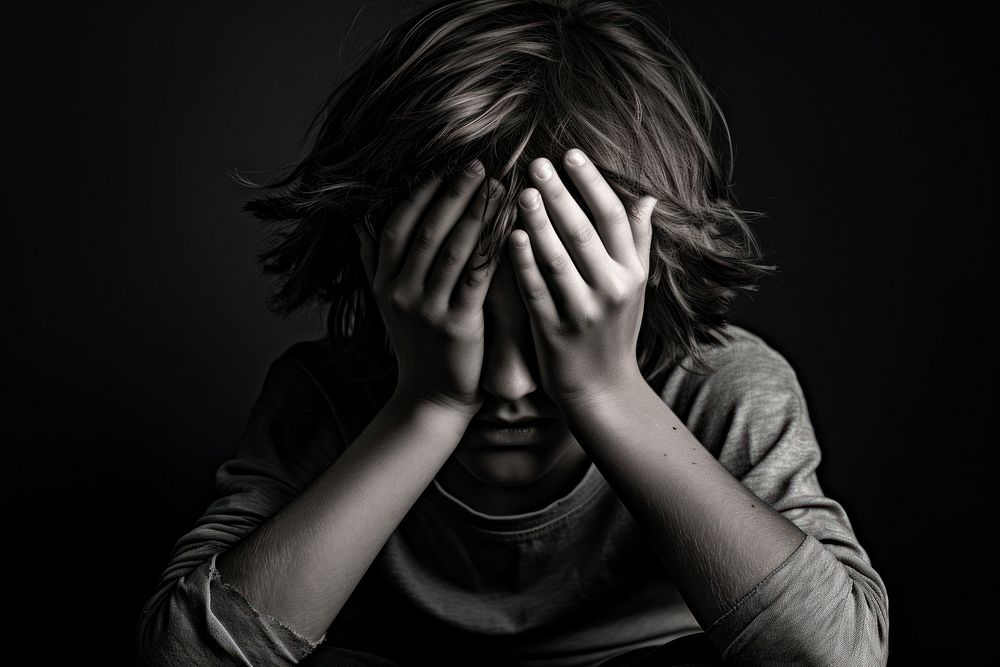A boy covering his face portrait worried adult.