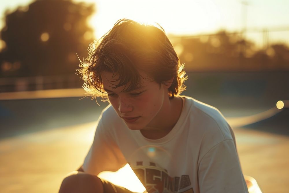 Teen man playing sketeboard portrait sunlight outdoors.