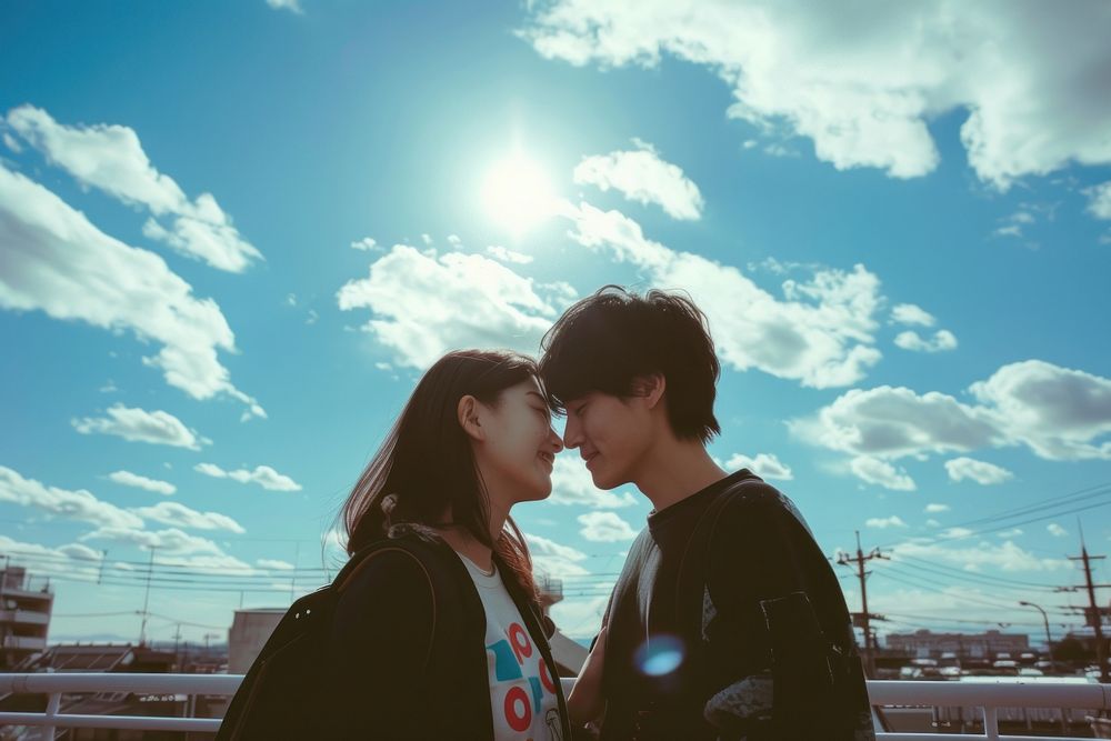 Photo of Japanese teenager couple portrait outdoors kissing.