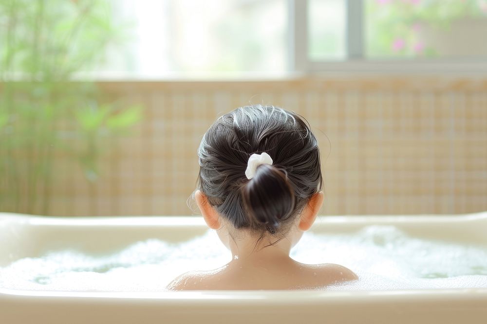 Photo of little asian kid in large tub bathtub back relaxation.