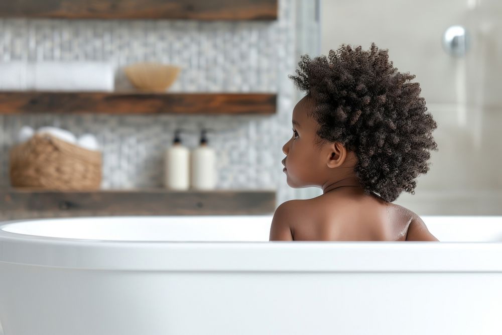 Photo of little black kid in large tub bathtub bathing back.