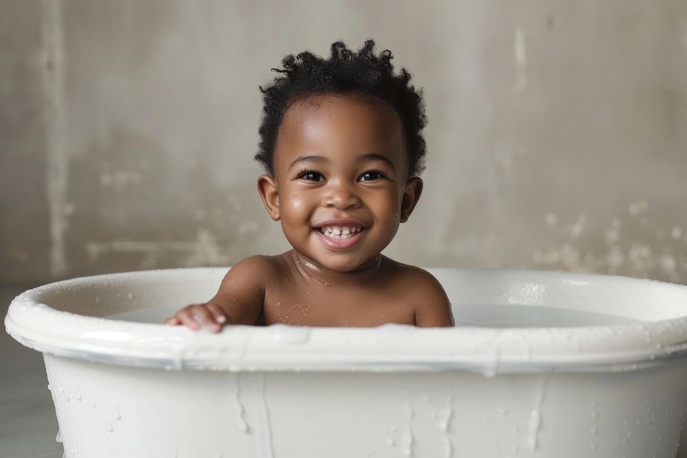 Photo of little black kid in large tub bathing bathtub smile.