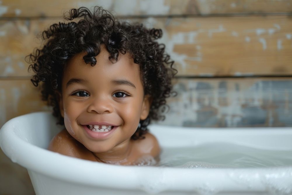 Photo of little black kid in large tub bathtub bathing smile.