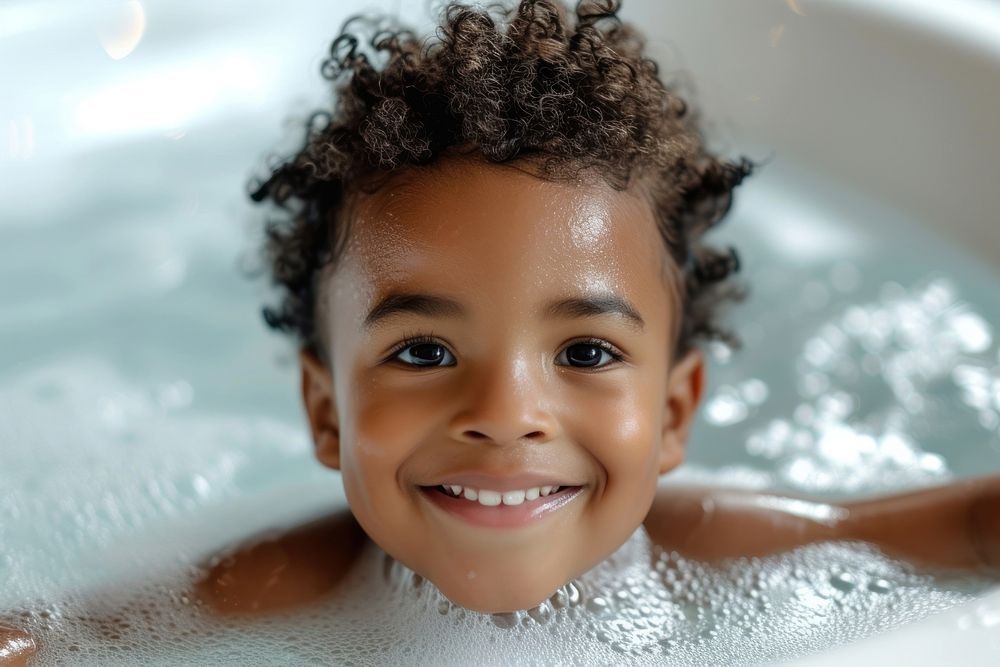 Photo of little black kid in large tub bathing smile happy.