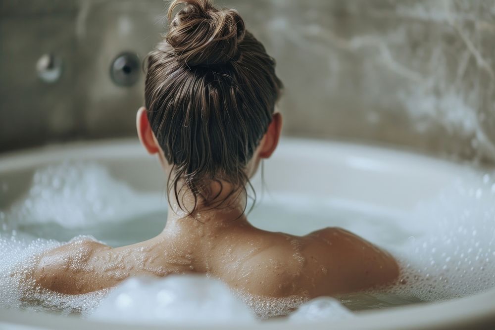 Photo of person in large tub bathtub bathing back.