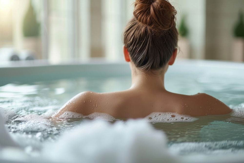 Photo of person in large tub bathtub jacuzzi bathing.