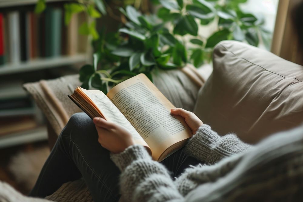 Photo of person reading book on sofa publication comfortable relaxation.