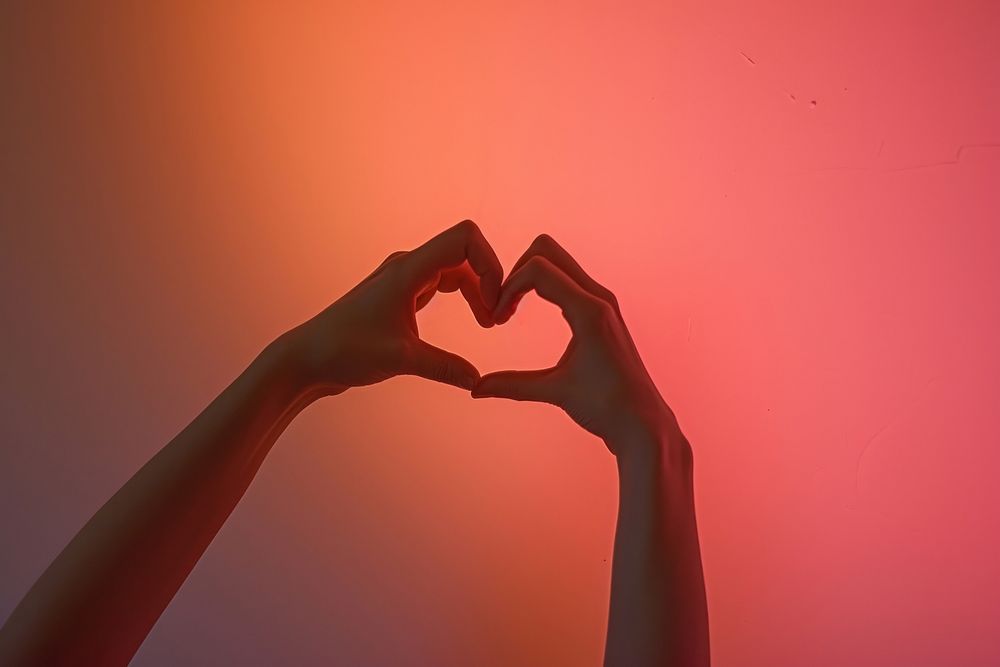 Silhouette hands doing heart pose adult pink red.