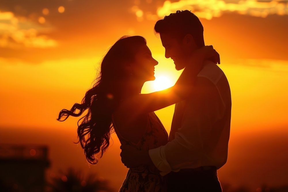 Middle eastern couple dancing backlighting outdoors smiling.