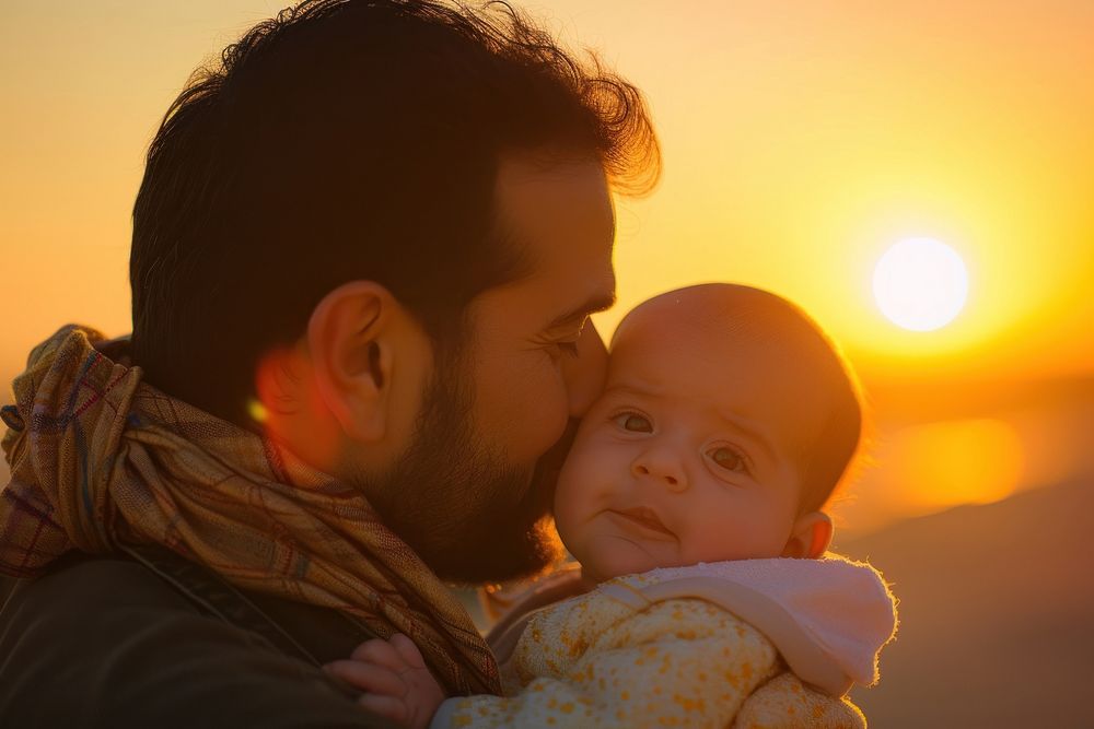 Middle eastern dad kissing new baby born sunset sunlight portrait.