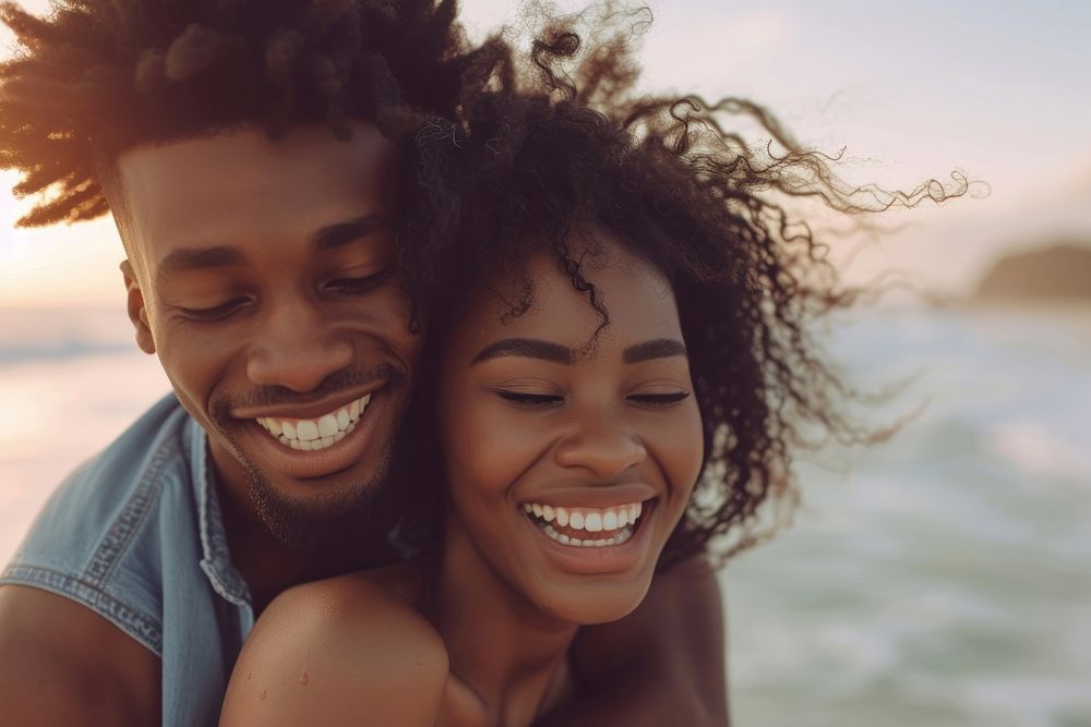 Black couple laughing sunset beach.