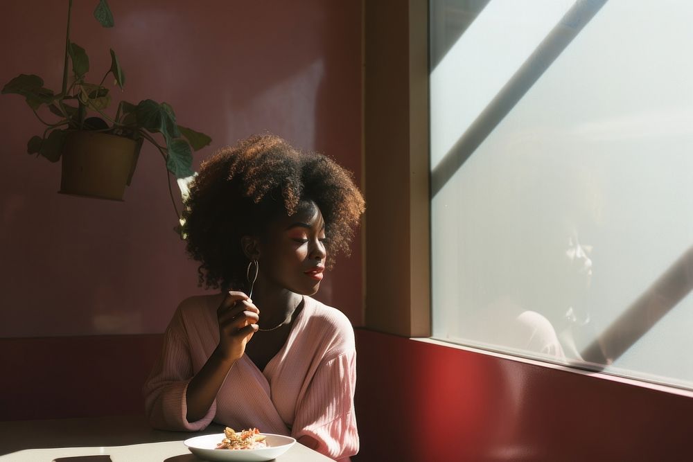 Black woman eating in a restaurant adult contemplation relaxation.