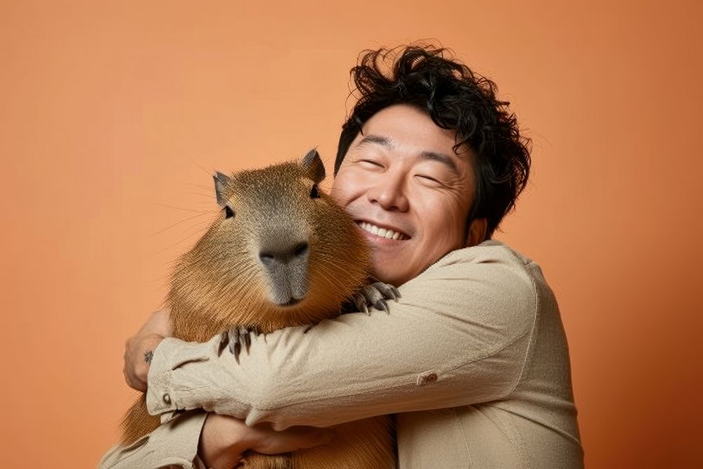 Adult east asian man hugging capybara portrait animal mammal.
