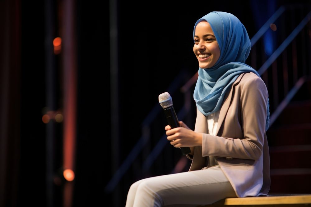 Young Muslim woman speaker on professional stage microphone smiling adult.