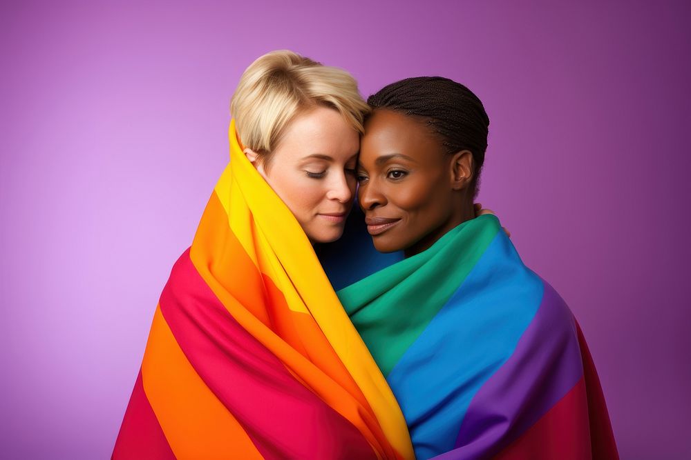 Cute gay sweethearts embracing wrapped in rainbow flag portrait hugging purple.