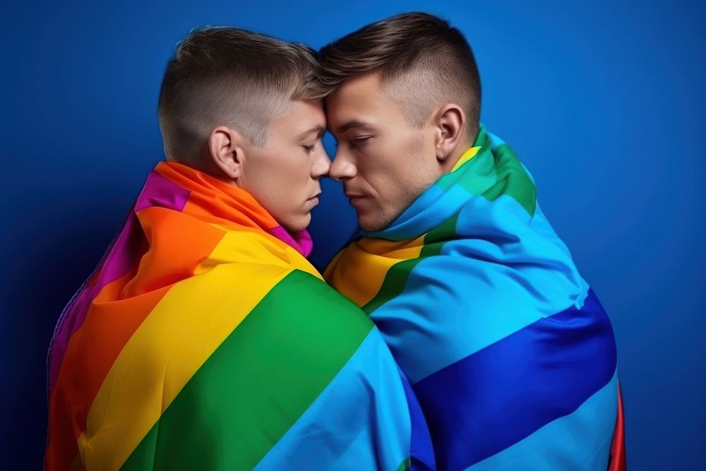 Cute gay sweethearts embracing wrapped in rainbow flag portrait adult togetherness.