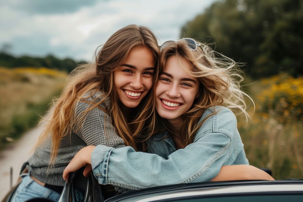 Woman with arm around female friend leaning on car laughing smile togetherness.