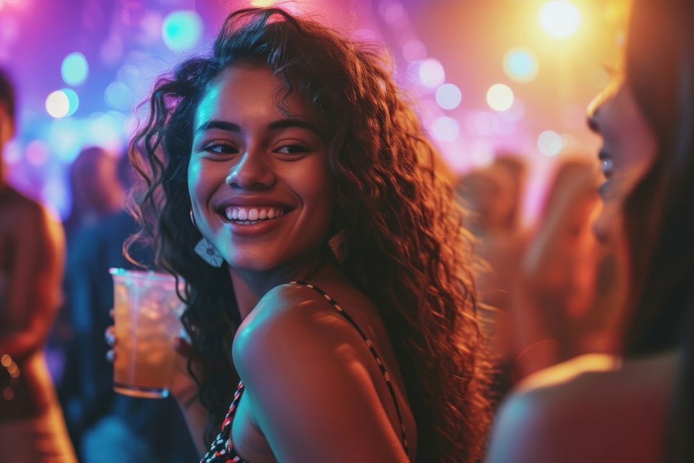 Carefree young woman with drink dancing by female friend enjoying at nightclub carefree smile party.