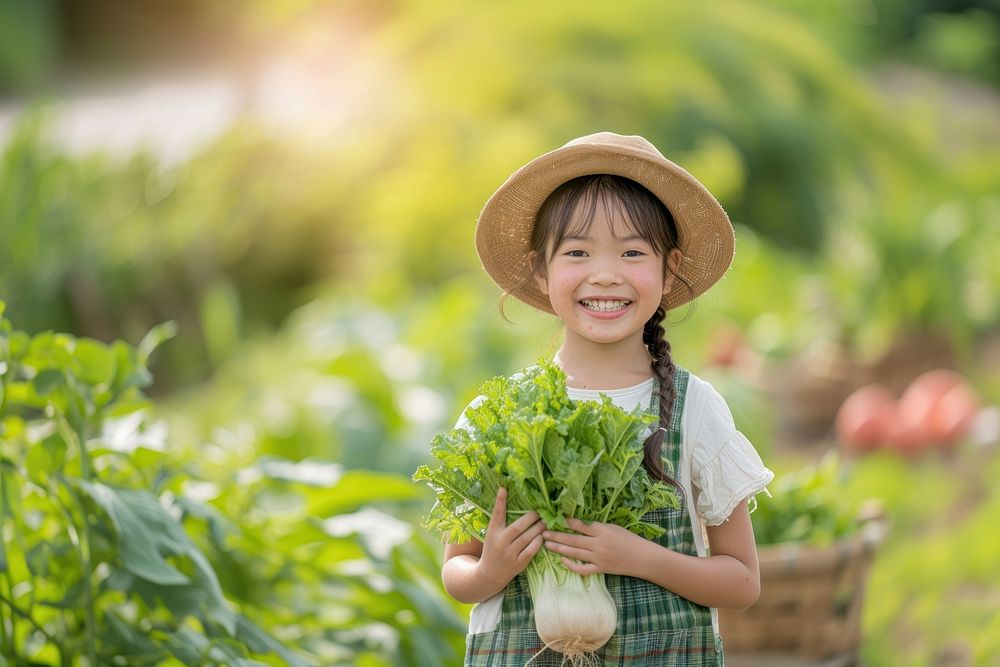 A happy japanese girl farmer holding vegetables organic plant child.