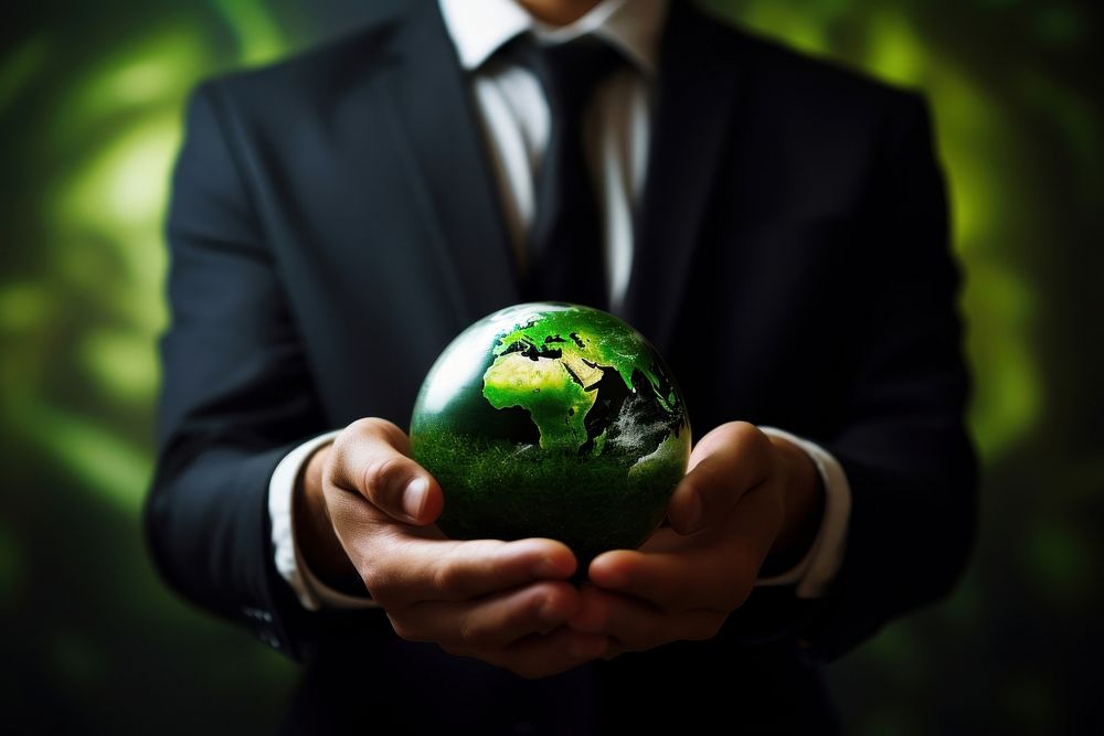 A man in a suit holding a small green grass globe sphere planet accessories.