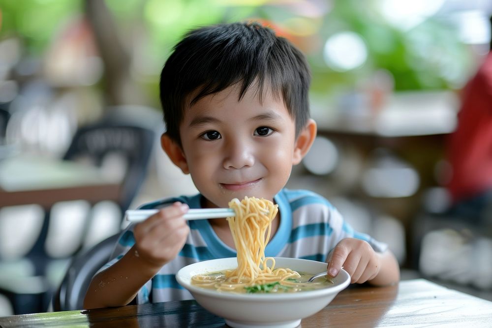 Thai boy eat noodle restaurant child food.