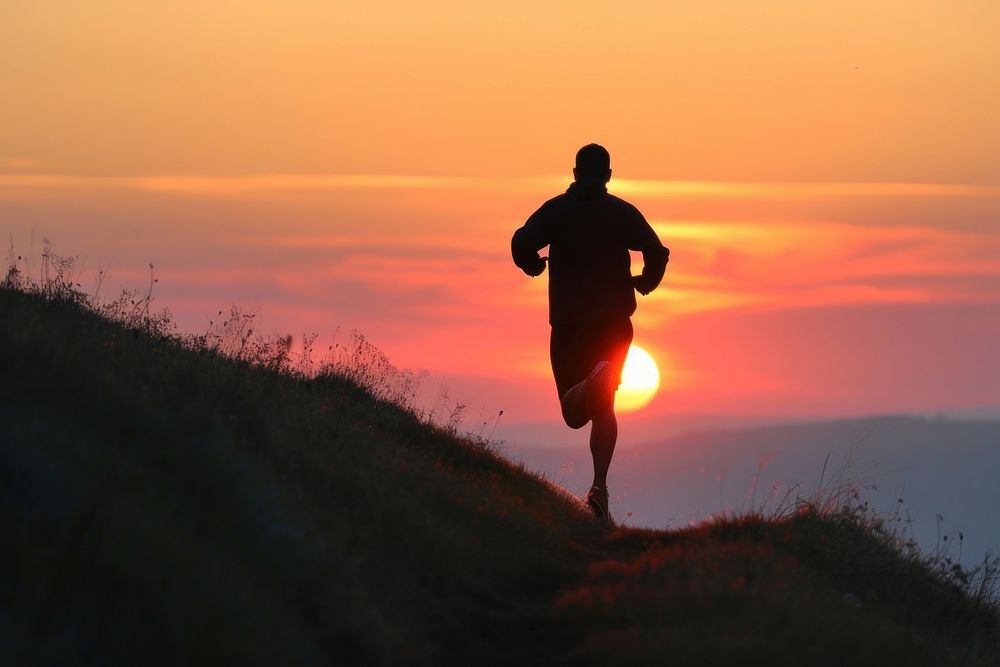 Man running up hillside backlighting silhouette jogging.