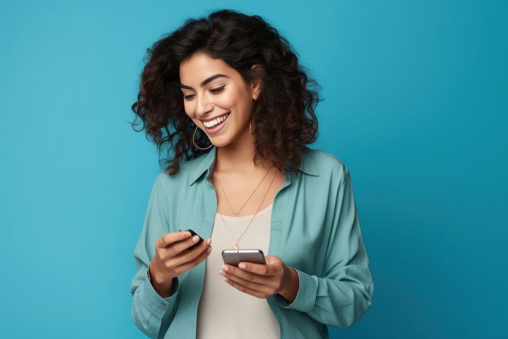 Latin woman holding mobile phone laughing smiling smile.