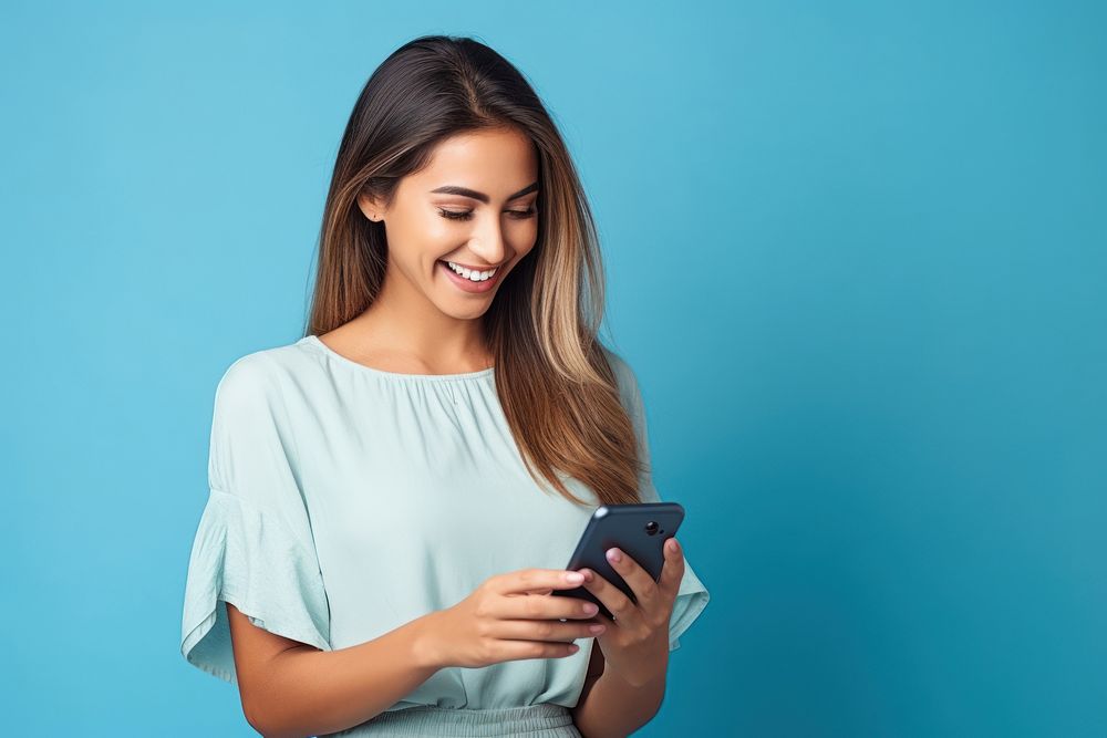 Latin woman holding mobile phone smiling adult happy.