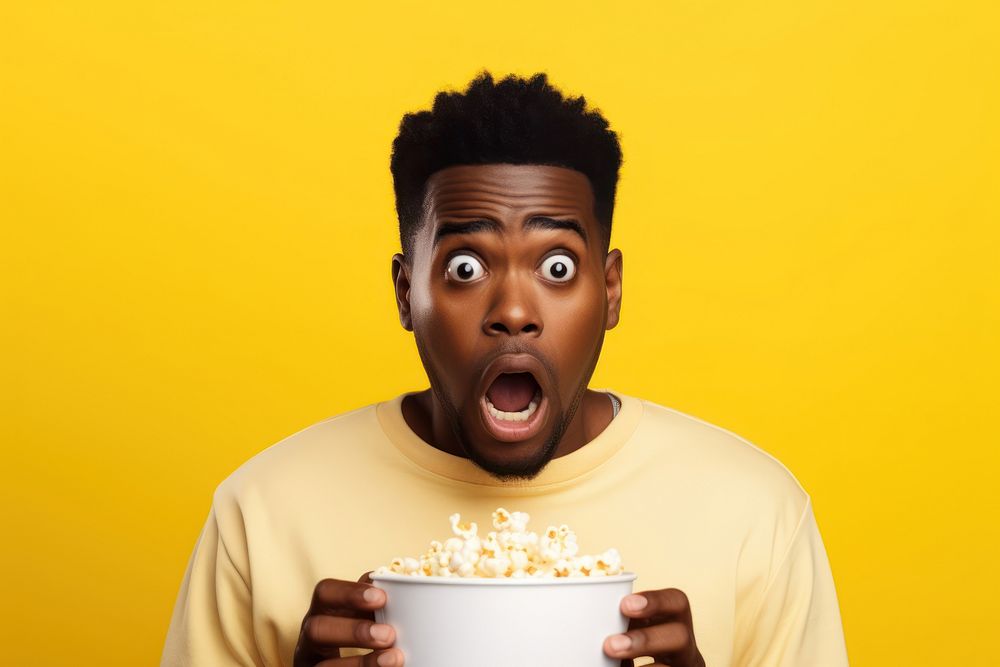 African american guy eating popcorn yellow shock gesturing.