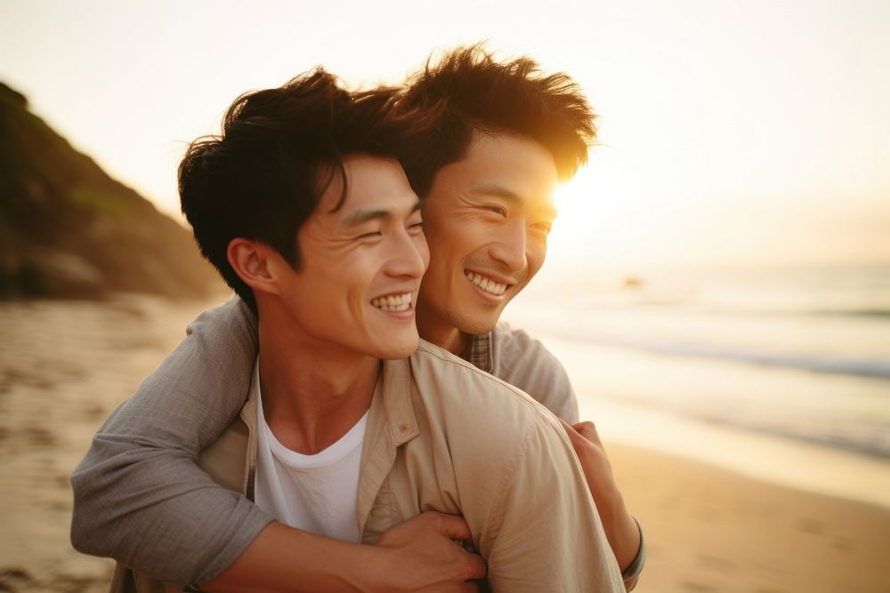 Korean gay couple portrait beach laughing.