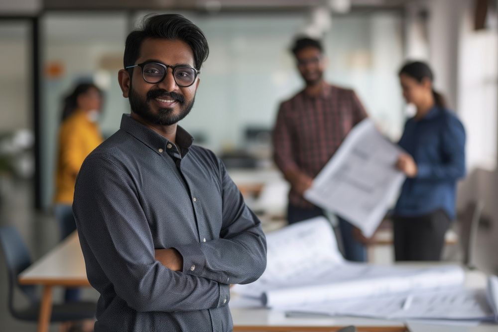 An Indian architect holding plans coworker glasses adult.