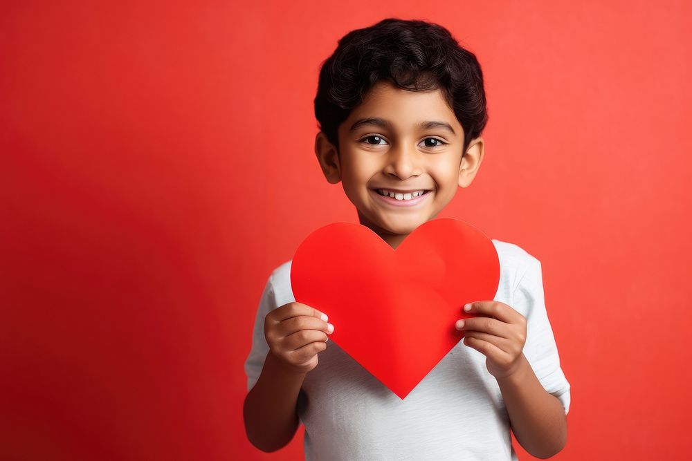 Indian kid holding a paper heart sports child love.