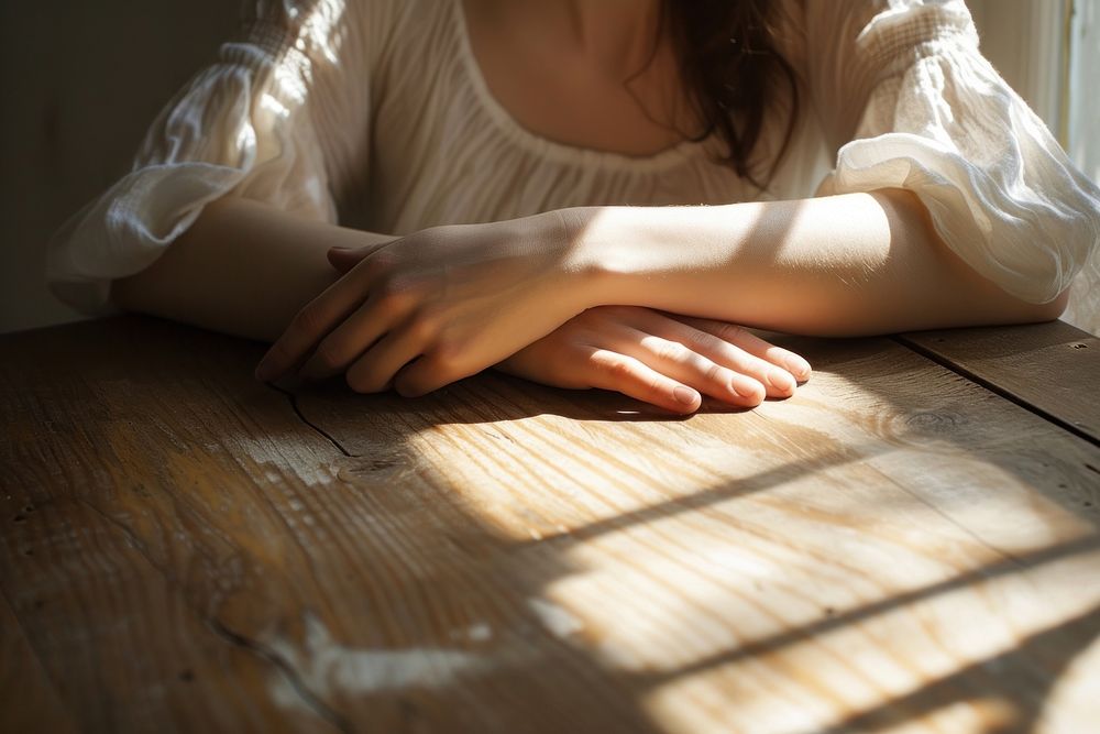 Woman arms on wooden table white contemplation loneliness.