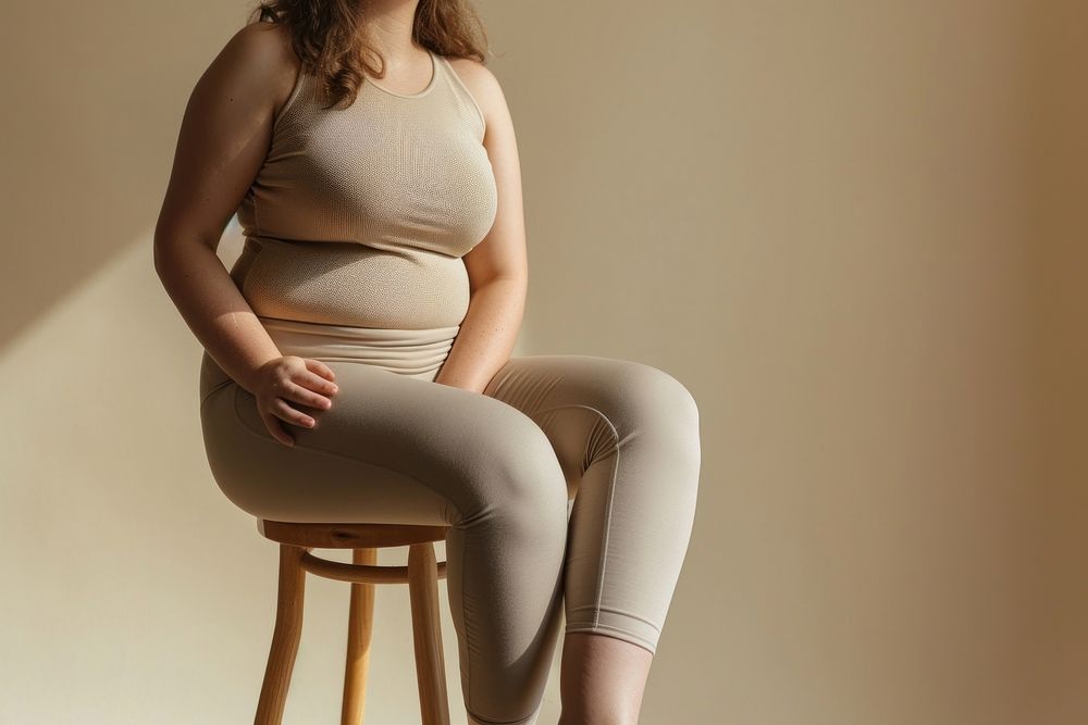 Chubby woman waist wearing exercise pants sitting adult undergarment.