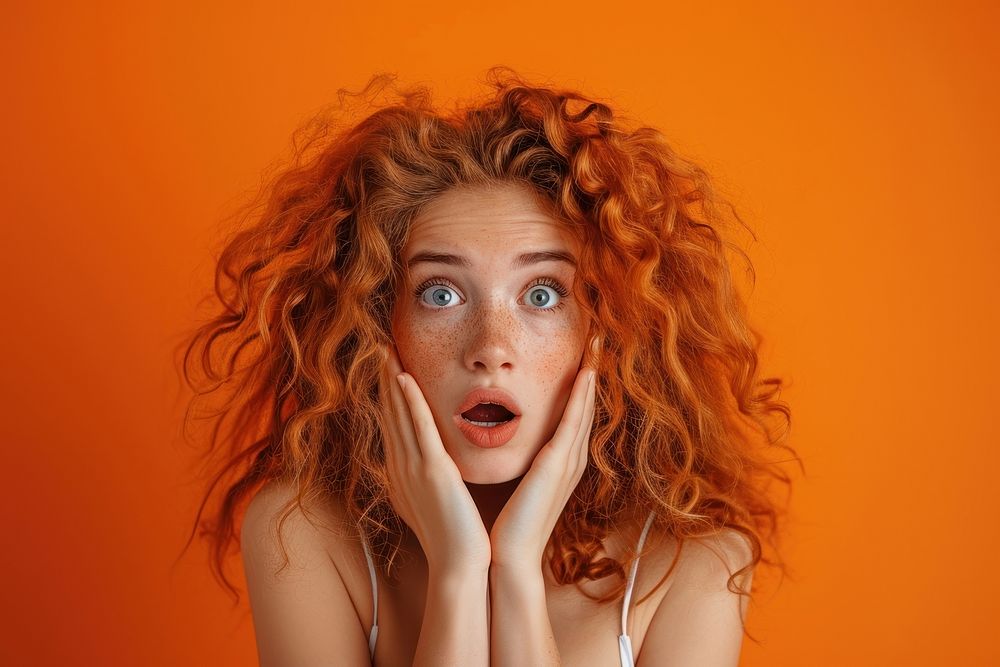 Surprised girl with Big Hair surprised adult orange background.