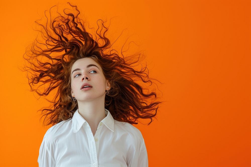 Surprised Woman white shirt with Big Hair adult woman orange background.
