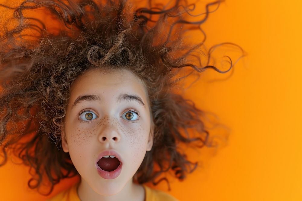 Surprised young girl with Big Hair surprised orange background dreadlocks.