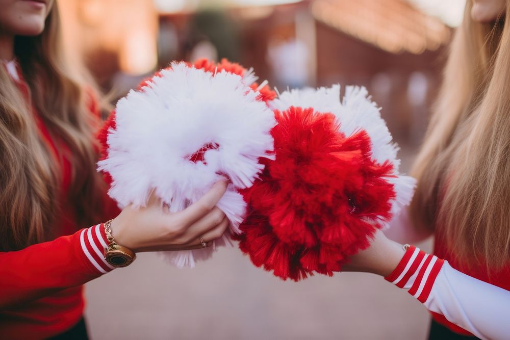 Two cheerleaders hands holding pom poms cheerleading togetherness celebration.