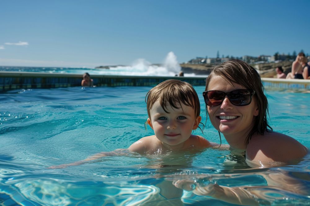 Kid and mother in icebergs pool sunglasses swimming outdoors.