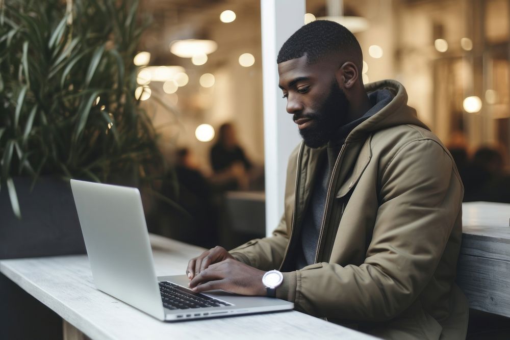 Black man uses laptop computer sitting adult.