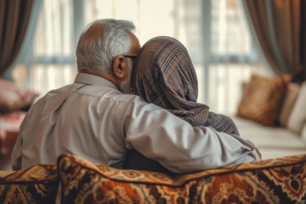 Senior Middle eastern couple hugging on sofa adult love affectionate.
