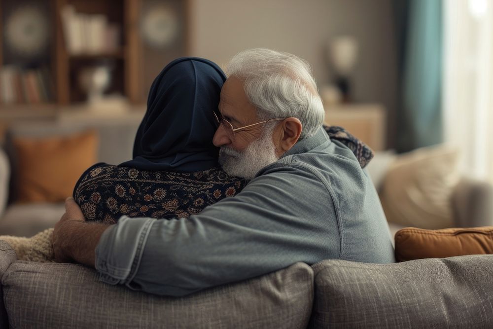 Senior Middle eastern couple hugging on sofa adult love affectionate.