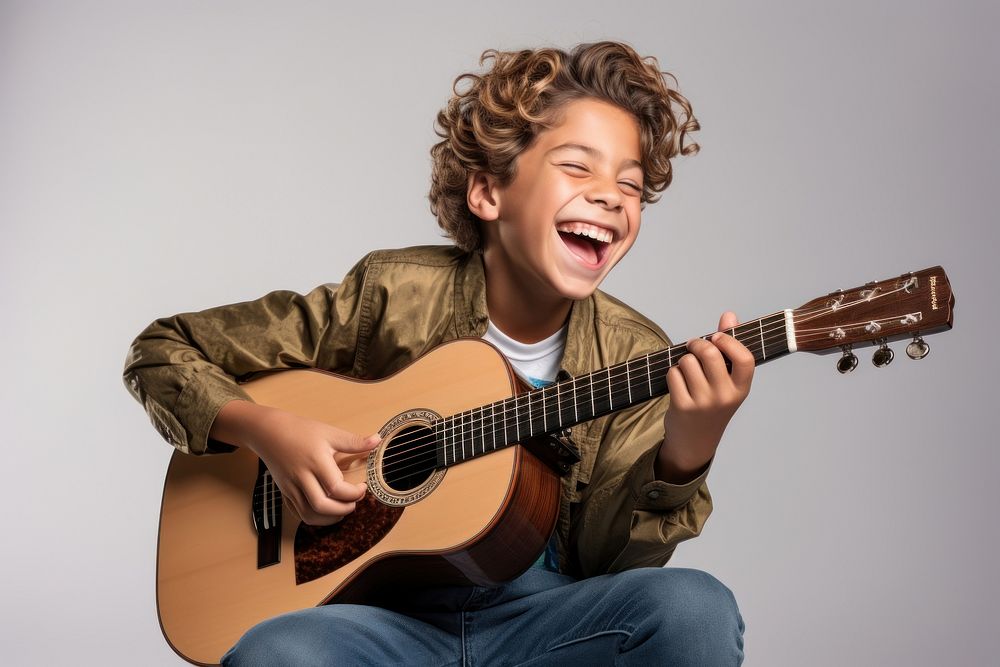Young boy playing acoustic guitar musician smiling happy.
