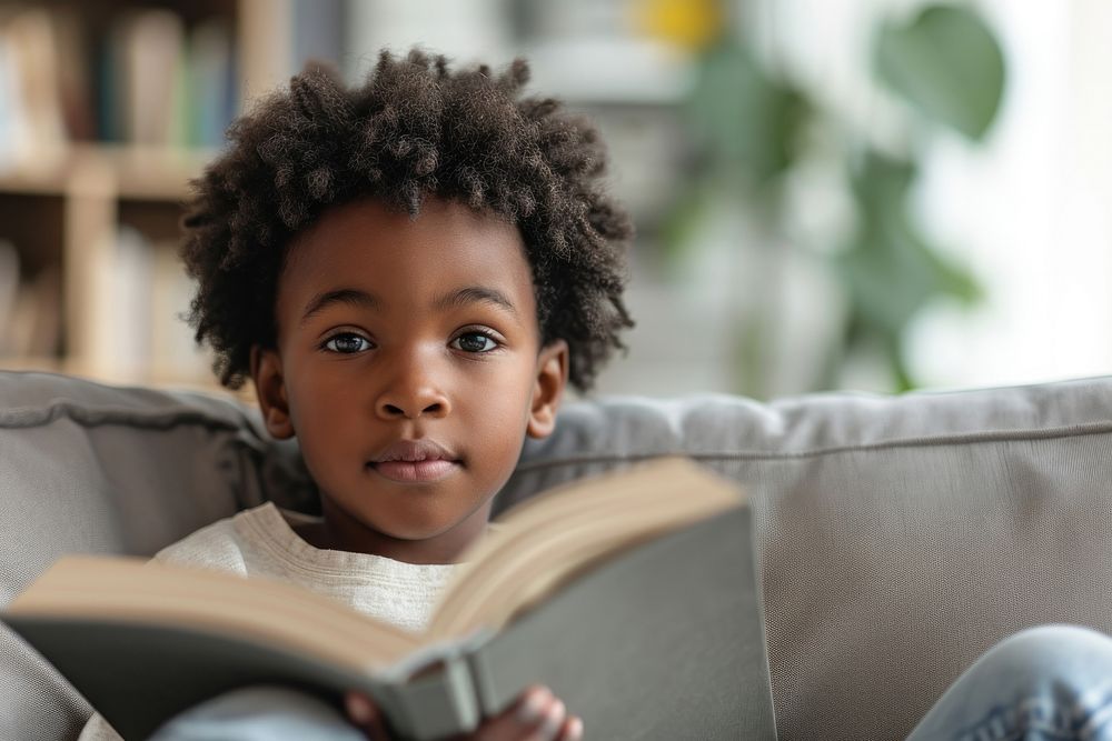 A cute african american boy on sofa reading child book.